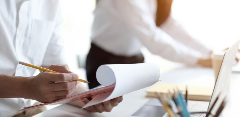 Pessoa verificando uma ficha técnica para aprovação caderno de requisitos