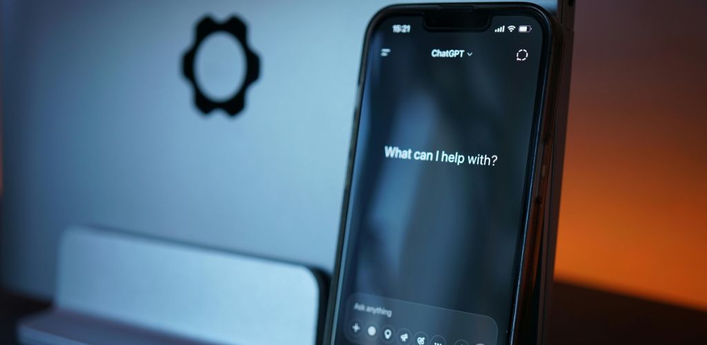 Smartphone mit geöffneter KI-Chatoberfläche und der Frage „What can I help with?“